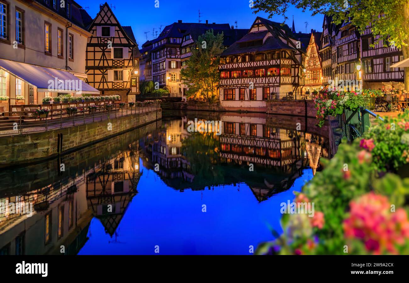 Maisons à colombages traditionnelles ornées avec fleurs fleuries le long des canaux dans le quartier de la petite France de Strasbourg, Alsace, France au coucher du soleil Banque D'Images