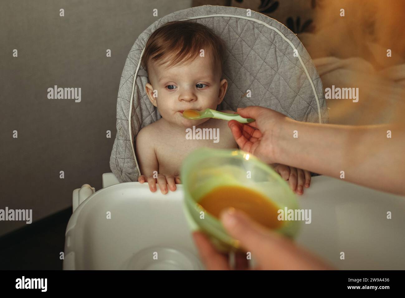 Un petit enfant mange de la purée de légumes. Maman nourrit le bébé. Banque D'Images