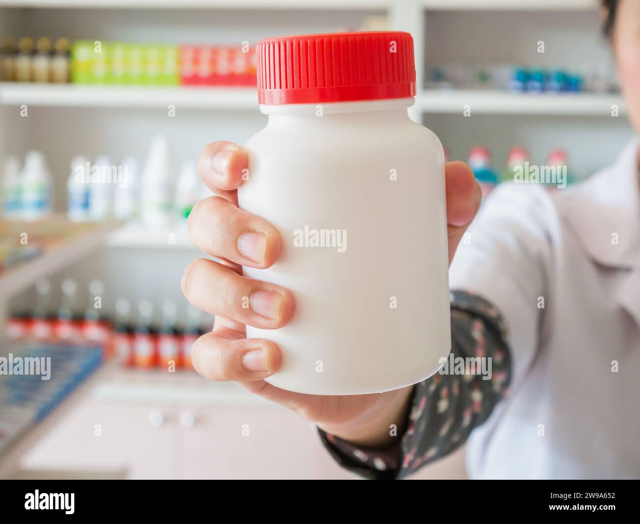 Pharmacien féminin tenir le flacon de médicament sur sa main dans le magasin de pharmacie Banque D'Images