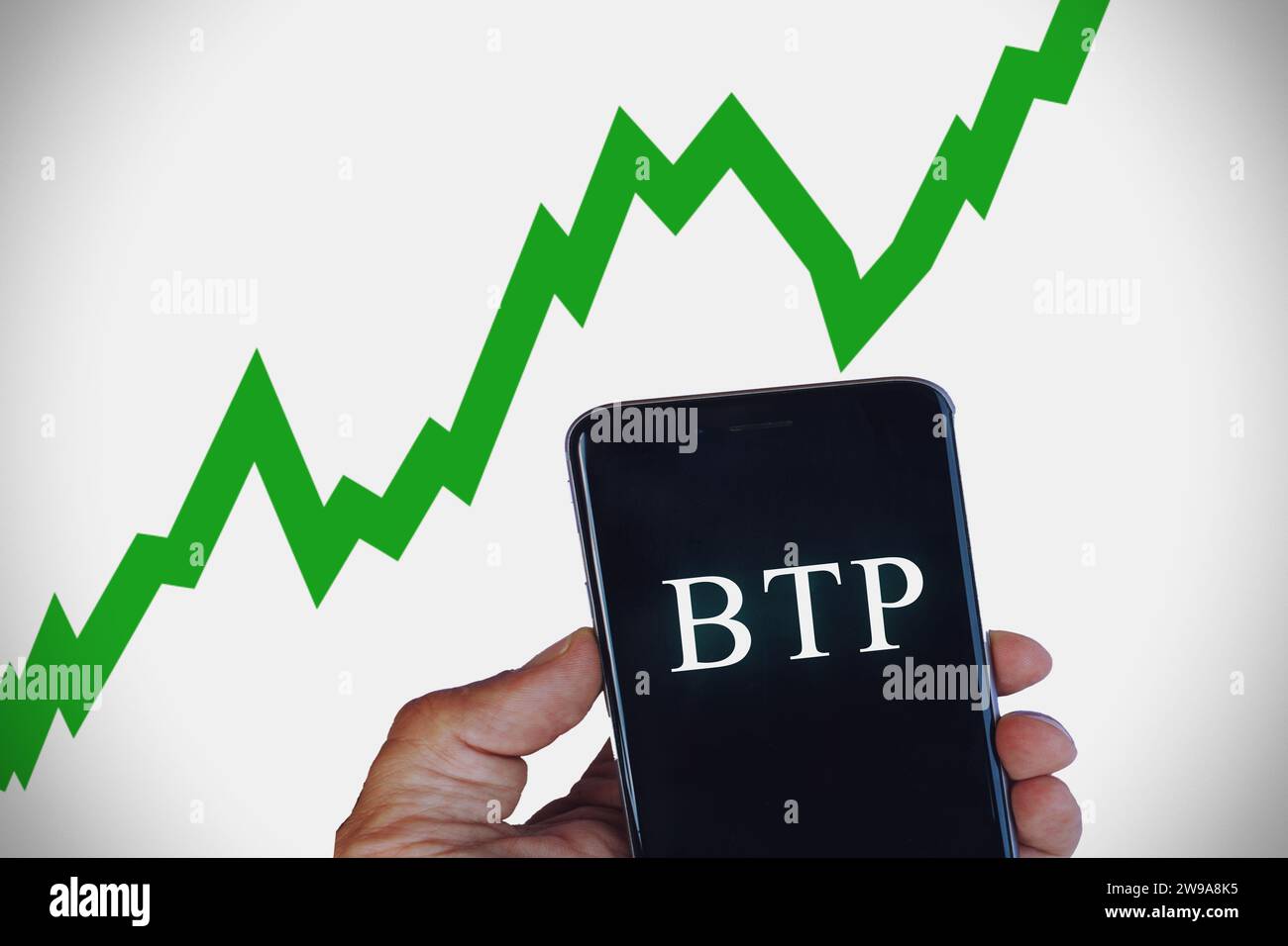 Main tenant un téléphone portable avec le texte « BTP » traduit par obligations d’État italiennes. Banque D'Images