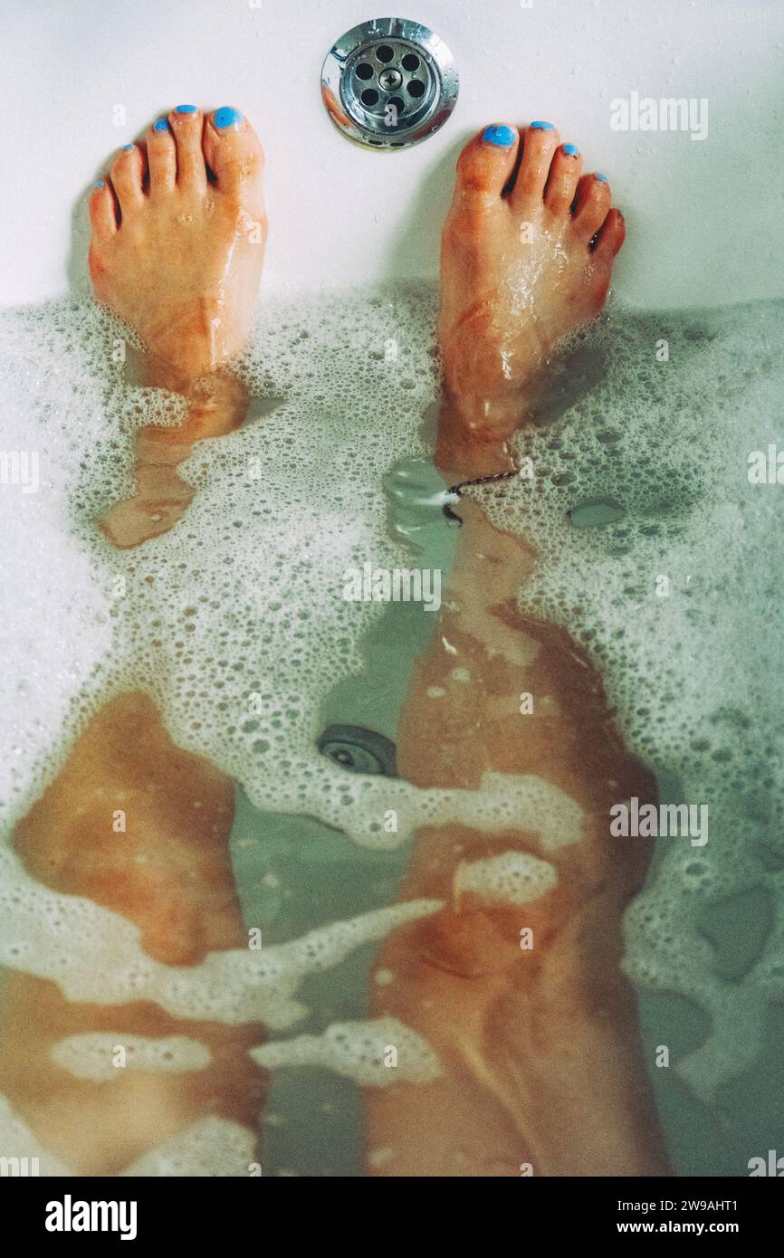 Femme se détendant dans un bain moussant avec des ongles bleus d'orteil Banque D'Images