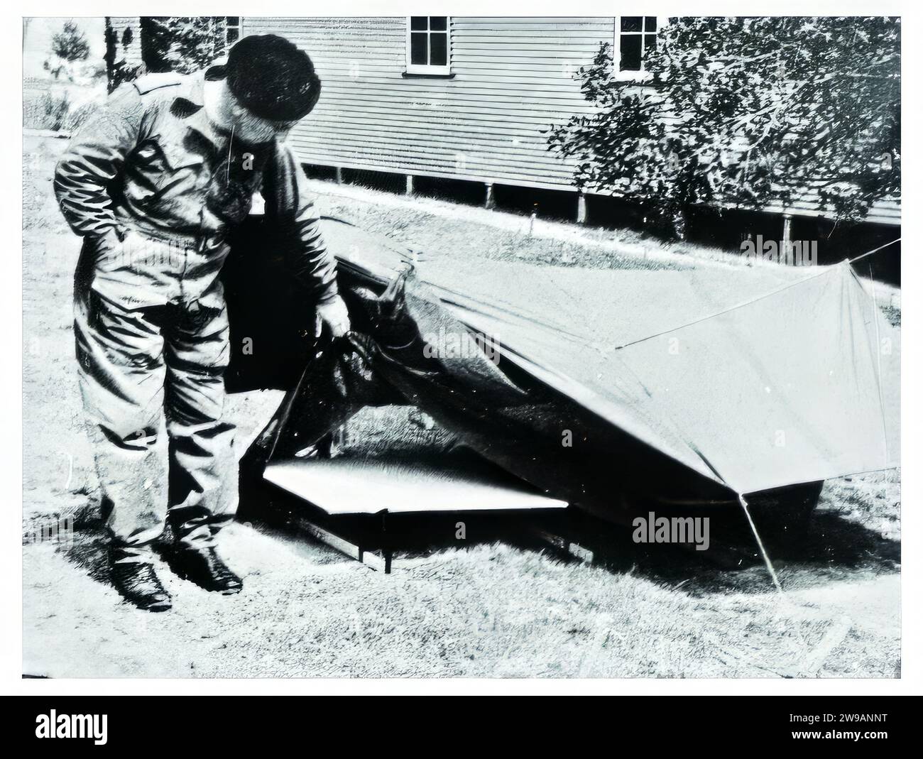 Le personnel technique de SRD à la station de recherche de Mount Martha fait la démonstration de la nouvelle « Semut Tent Fly ». Fait de tissu de ballon de coton traité pour être imperméable et pourri, la mouche de tente était juste une partie du système. Il comprenait également une moustiquaire légère portative et une plate-forme de couchage inclinée qui non seulement empêchait l'occupant de la tente de se trouver en grande partie à l'écart de la boue et de la boue, mais lui a également permis de jaillir dans l'action beaucoup plus rapidement que de l'intérieur des hamacs de jungle entièrement clos qui étaient stadard question aux agents de SRD. Banque D'Images
