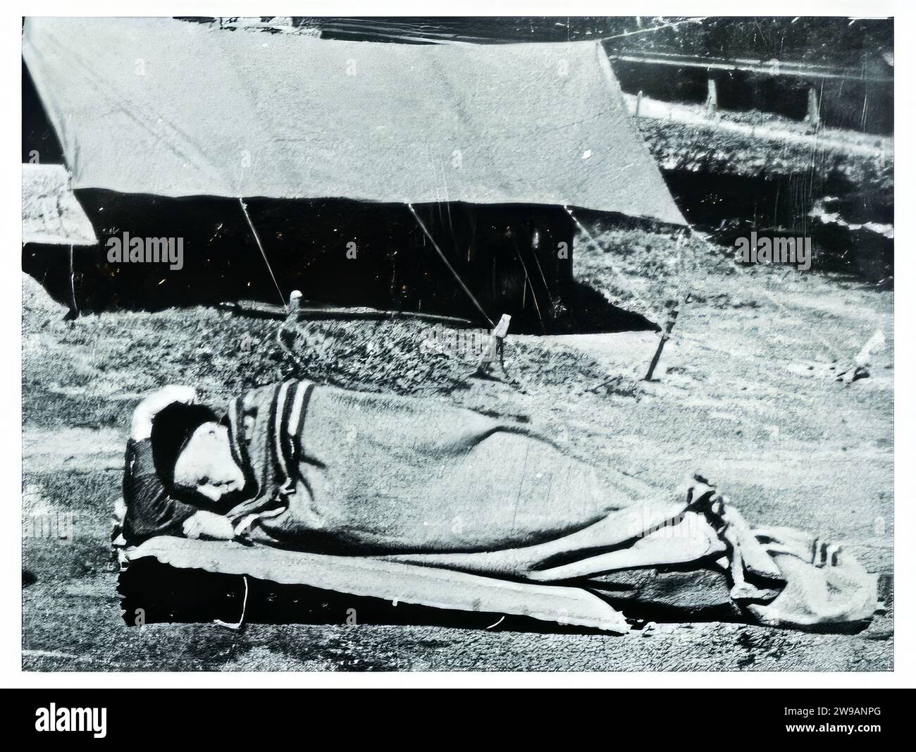 Le personnel technique de SRD à la station de recherche de Mount Martha fait la démonstration de la nouvelle « Semut Tent Fly ». Fait de tissu de ballon de coton traité pour être imperméable et pourri, la mouche de tente était juste une partie du système. Il comprenait également une moustiquaire légère portative et une plate-forme de couchage inclinée qui non seulement empêchait l'occupant de la tente de se trouver en grande partie à l'écart de la boue et de la boue, mais lui a également permis de jaillir dans l'action beaucoup plus rapidement que de l'intérieur des hamacs de jungle entièrement clos qui étaient stadard question aux agents de SRD. Banque D'Images