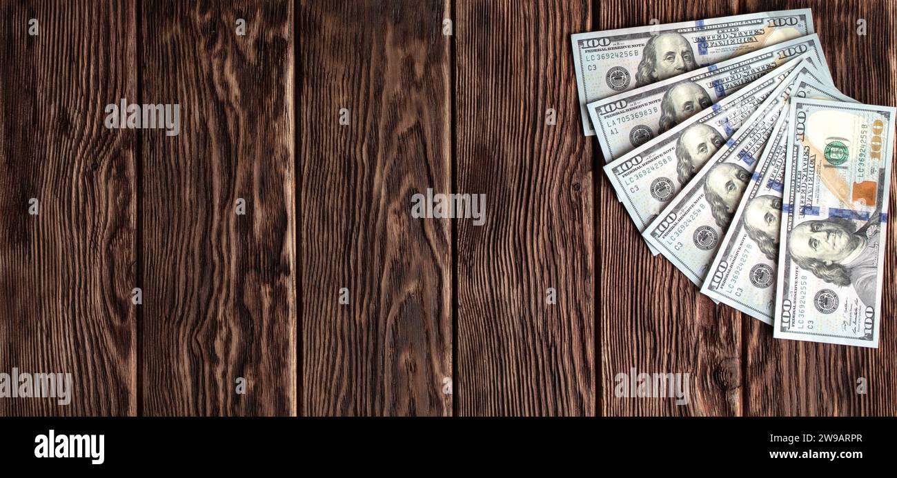Billets de cent dollars sur un fond en bois de planches brunes avec une texture prononcée Banque D'Images