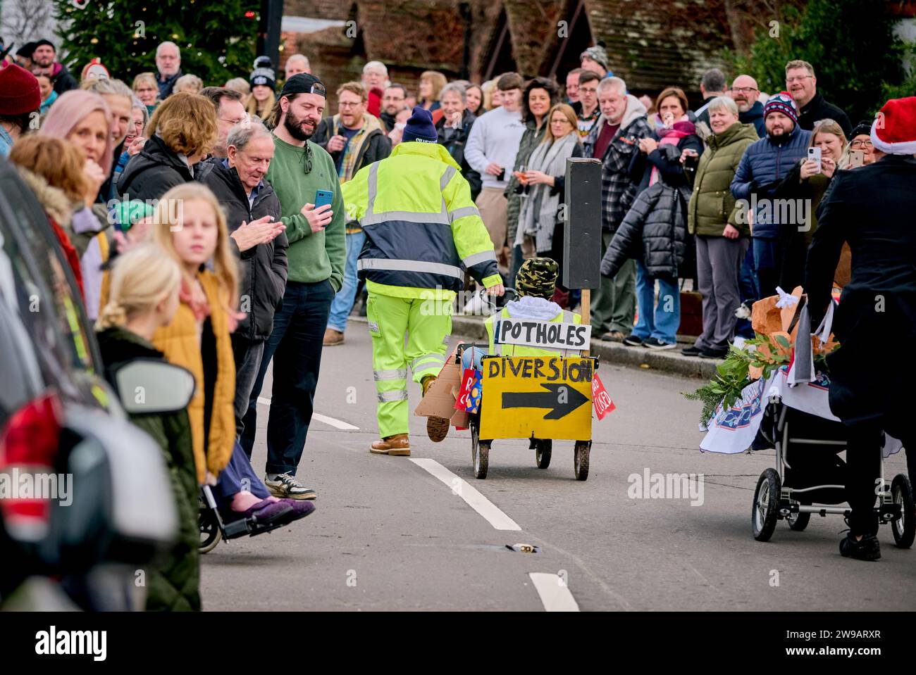 East Hoathly, Royaume-Uni. 26 décembre 2023. Course de poussettes le lendemain de Noël : des équipes en robe de fantaisie font la course dans le village d'East Hoathly dans l'East Sussex pour recueillir des fonds pour des œuvres caritatives locales. L'événement annuel commence et se termine au pub Kings Head au centre du village. Crédit : Jim Holden/Alamy Live News Banque D'Images