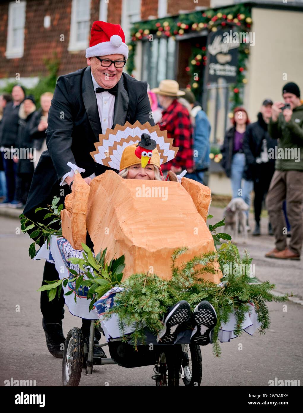 East Hoathly, Royaume-Uni. 26 décembre 2023. Course de poussettes le lendemain de Noël : des équipes en robe de fantaisie font la course dans le village d'East Hoathly dans l'East Sussex pour recueillir des fonds pour des œuvres caritatives locales. L'événement annuel commence et se termine au pub Kings Head au centre du village. Crédit : Jim Holden/Alamy Live News Banque D'Images