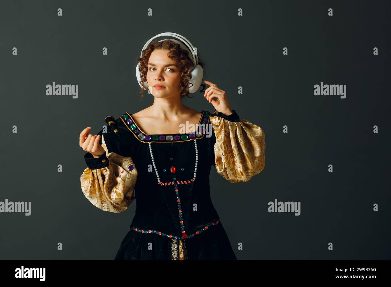 Portrait d'une jeune femme avec des écouteurs sur la tête et vêtue d'une robe vintage écoute de la musique Banque D'Images