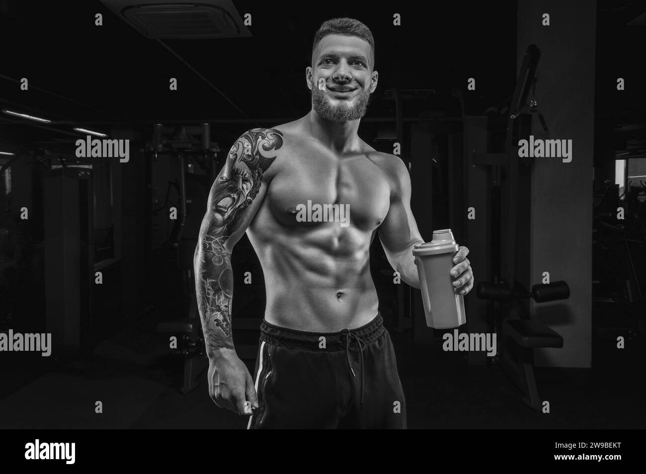 Portrait d'un athlète debout avec un shaker dans la salle de gym. Culturisme et concept de fitness. Supports mixtes Banque D'Images