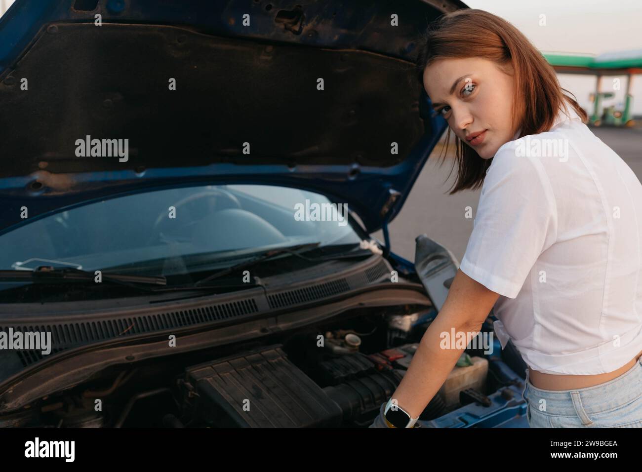 Jeune belle fille chaude mécanicien automobile verse l'huile, réparation de voiture tout en voyageant, panne de voiture Banque D'Images