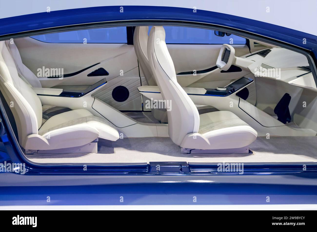 Vue latérale de l'intérieur futuriste de la voiture avec des sièges confortables avec appuie-tête dans le corps de couleur bleue et tableau de bord remplaçant le volant en usine sous la lumière Banque D'Images