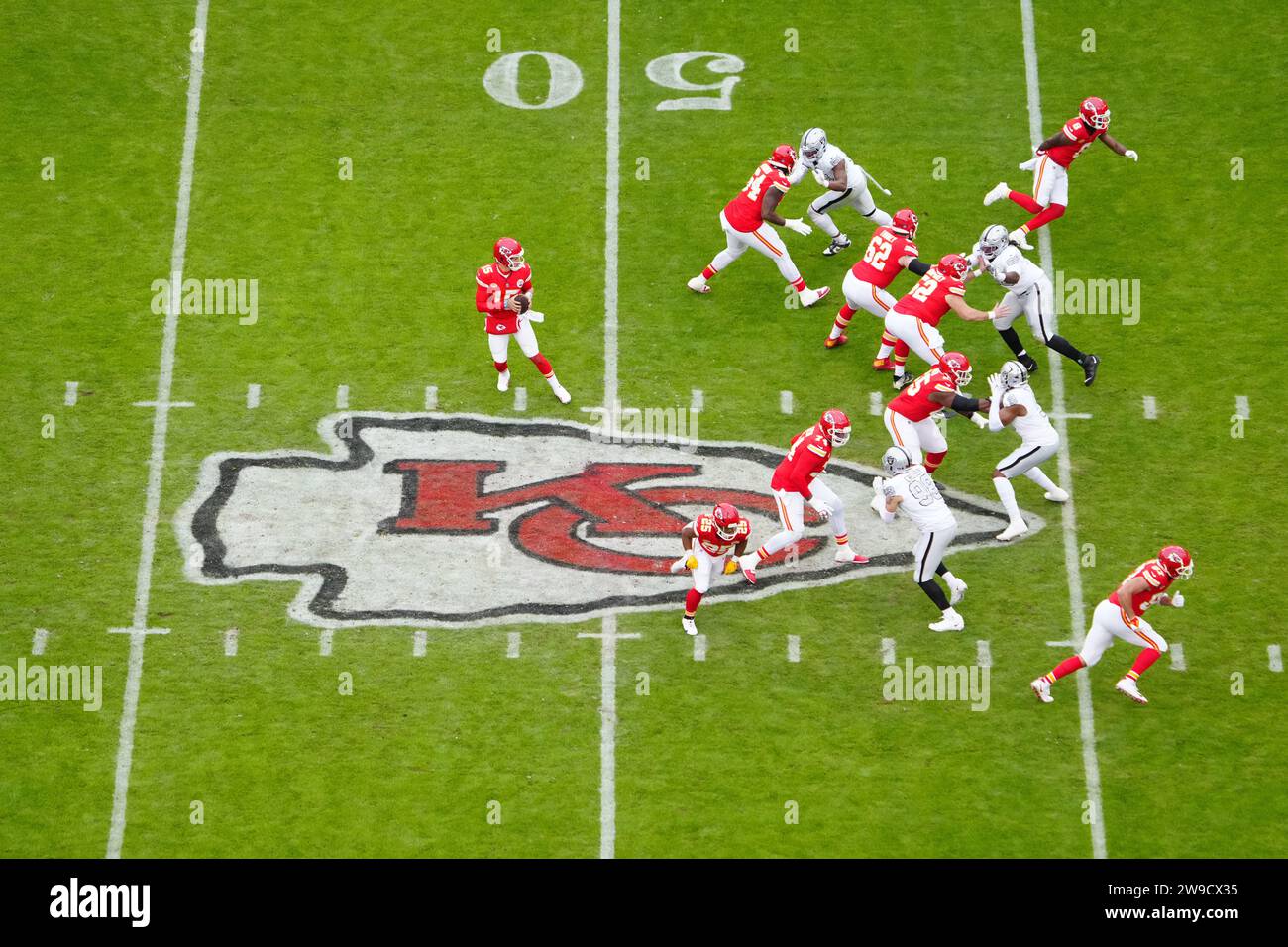 Une vue d'ensemble comme le quarterback des Chiefs de Kansas City Patrick Mahomes (15) prend le coup sur la ligne de scrimmage sur le logo des Chiefs au milieu de terrain contre les Raiders de Las Vegas lors d'un match de football de la NFL, lundi, 25 décembre 2023, à Kansas City, Mo. Les Raiders ont battu les Chiefs 20-14. Banque D'Images