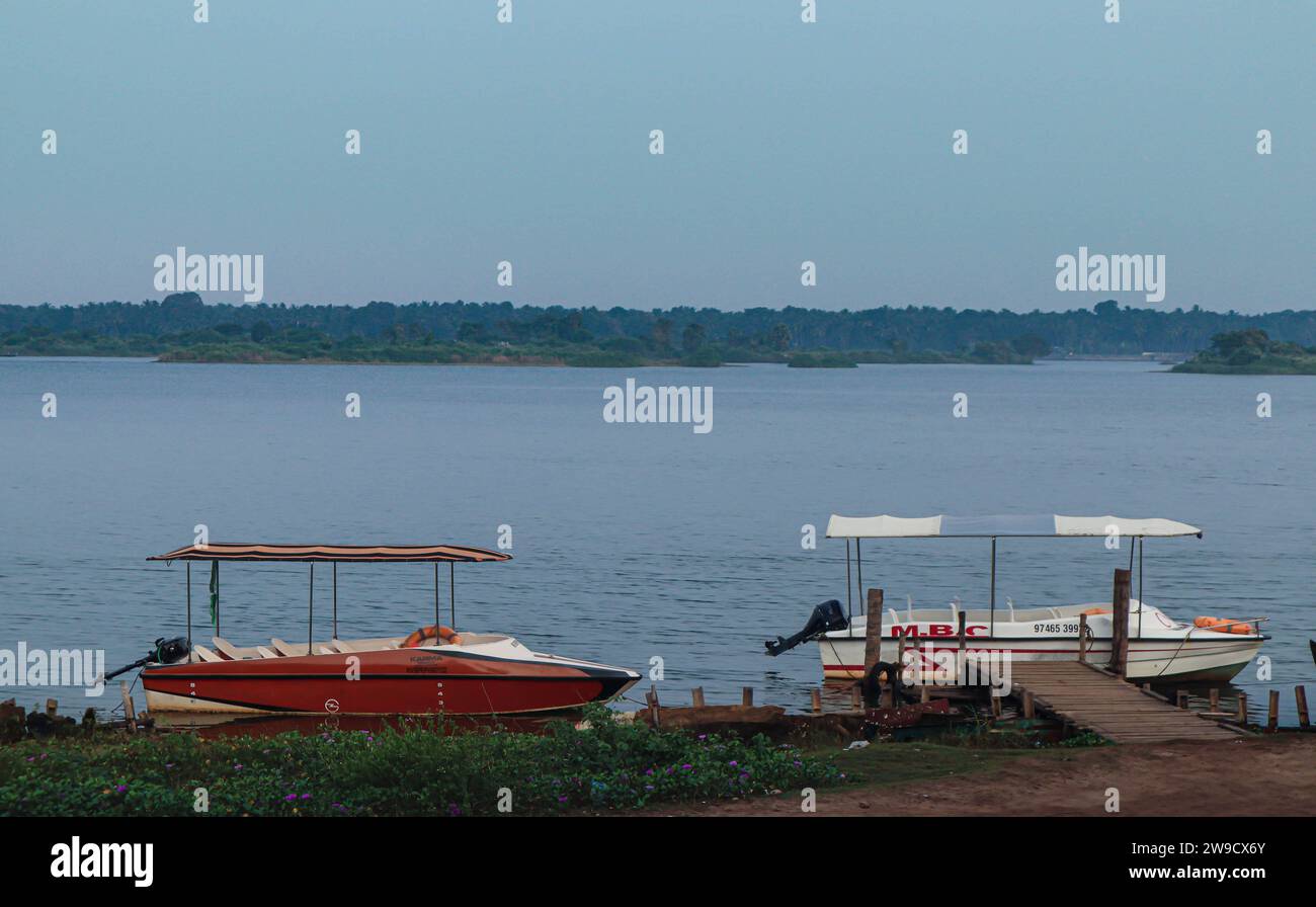 Les bateaux se reposent au bord du lac tranquille, leurs reflets reflétant les douces teintes du crépuscule. Banque D'Images