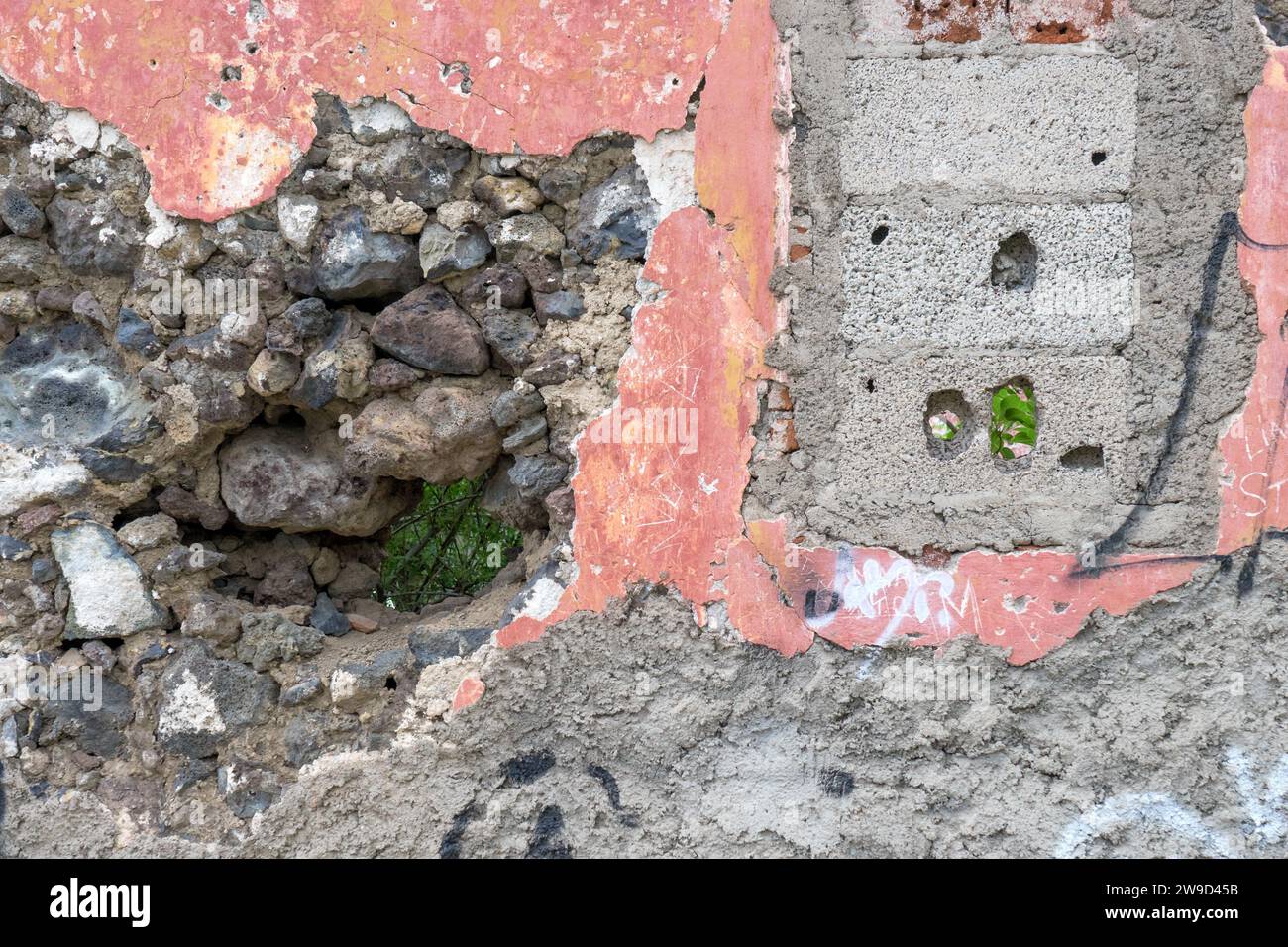 Détail d'un mur de maison coloré détruit avec des pierres et des trous Banque D'Images
