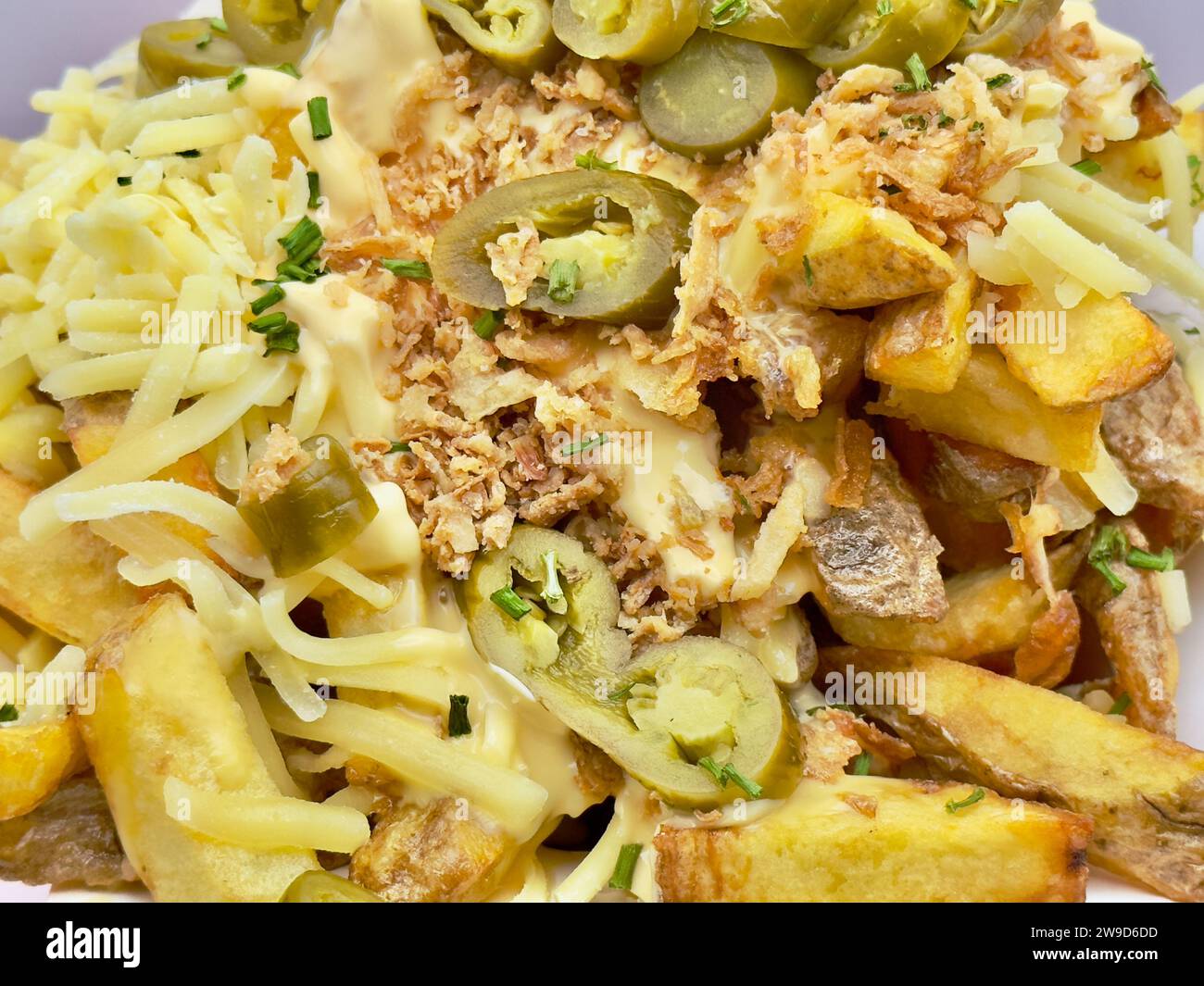 Un panier en osier rempli de pommes de terre cuites recouvertes de fromage fondu Banque D'Images