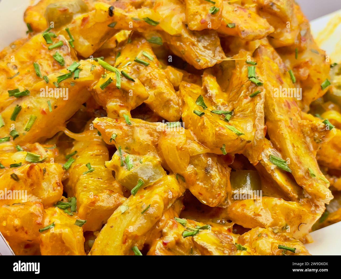 Un panier en osier rempli de pommes de terre cuites recouvertes de fromage fondu Banque D'Images