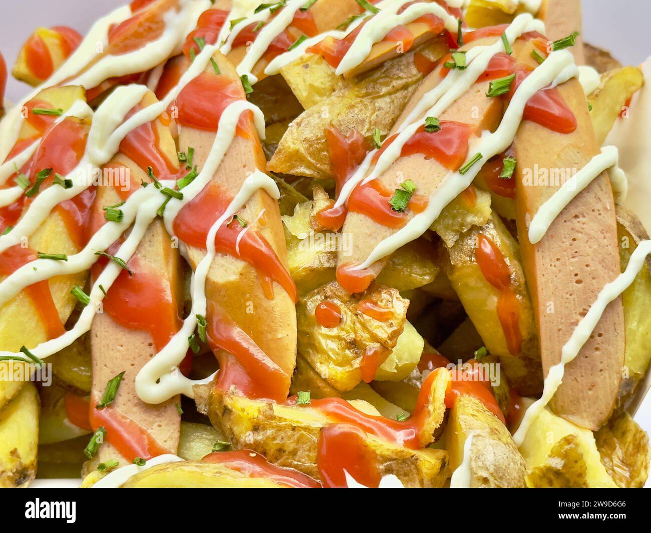 Un panier en osier rempli de pommes de terre cuites recouvertes de fromage fondu Banque D'Images