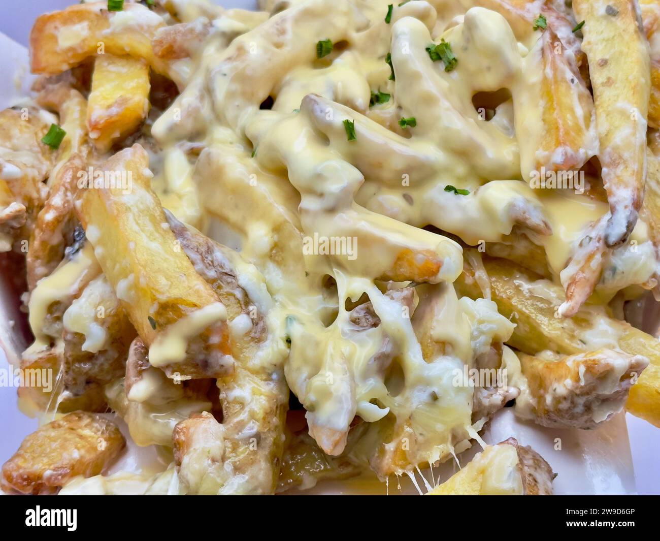 Un panier en osier rempli de pommes de terre cuites recouvertes de fromage fondu Banque D'Images