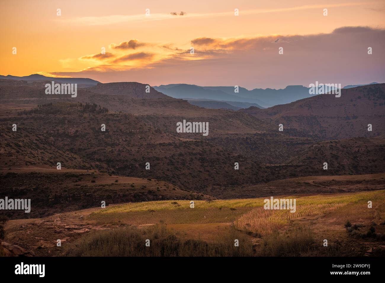 Le soleil se couche sur des couches de montagnes et un champ de cultures dans le Lesotho rural Banque D'Images