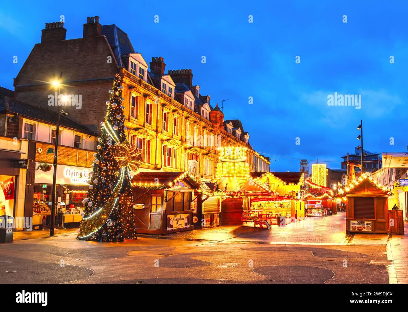 Bromley, Grand Londres, Angleterre - 27 décembre 2023 : le marché de Noël de Bromley brille à l'aube, orné de teintes chaudes. Le ciel bleu encadre des lumières festives Banque D'Images