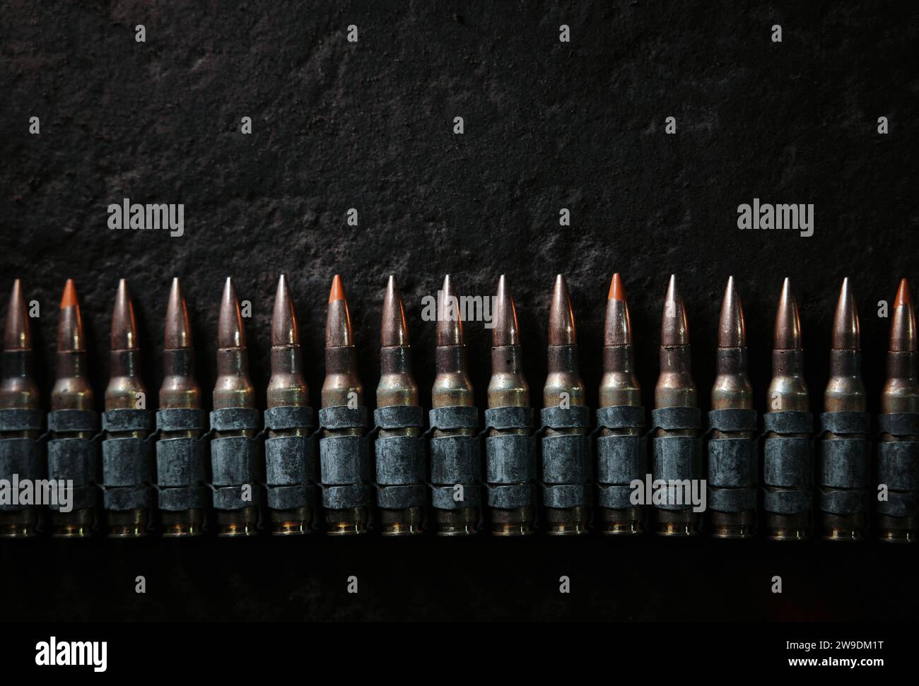 Ceinture de balle de mitrailleuse sur le sol. Contexte sur le thème militaire. Munitions, chaîne de munitions sur fond béton. Vue de dessus de la courroie de mitrailleuse Banque D'Images