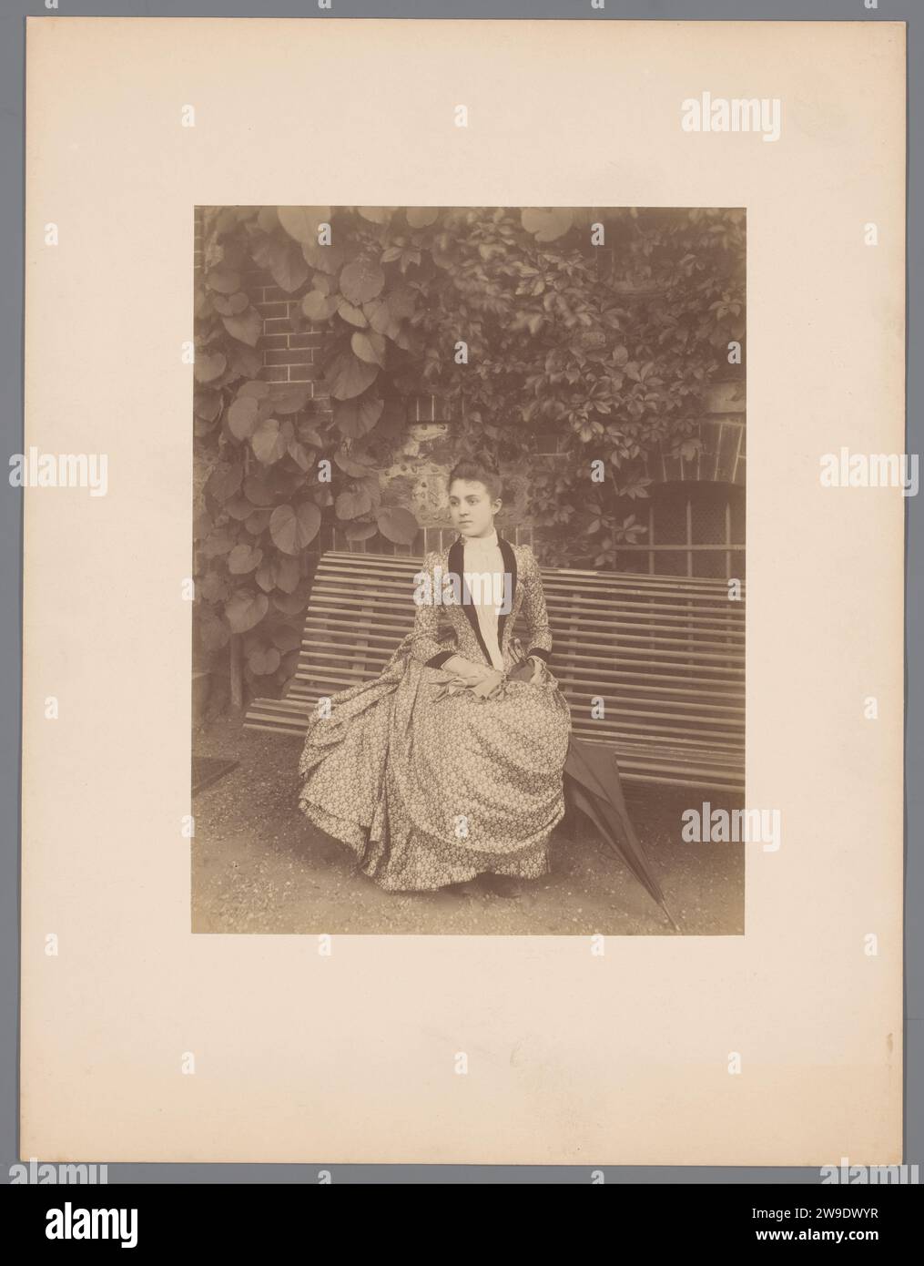 Portrait d'une jeune femme assise dans un jardin ou un parc, c. 1890 - c. 1900 photographie Portrait d'une jeune femme assise sur un banc dans un jardin ou un parc. La femme porte une robe décente et un parapluie à côté d'elle et regarde vers la gauche après la caméra. Même jardin que le RP-F-00-6050 N RP-F-00-6051. Papier France. support photographique. impression d'albumen sur carton Banque D'Images