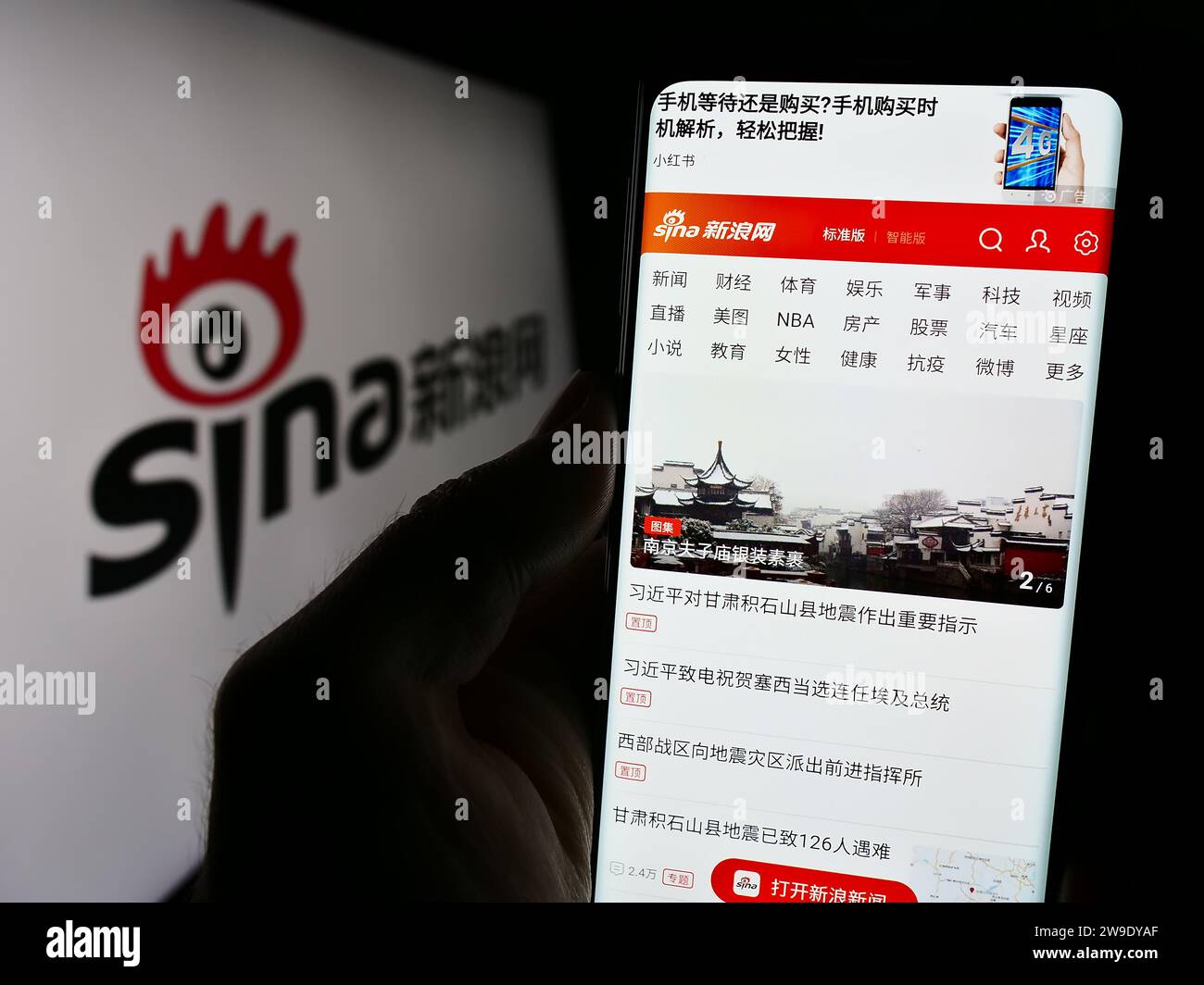 Personne tenant le téléphone portable avec la page Web de la société de technologie chinoise Sina Corporation en face du logo. Concentrez-vous sur le centre de l'écran du téléphone. Banque D'Images