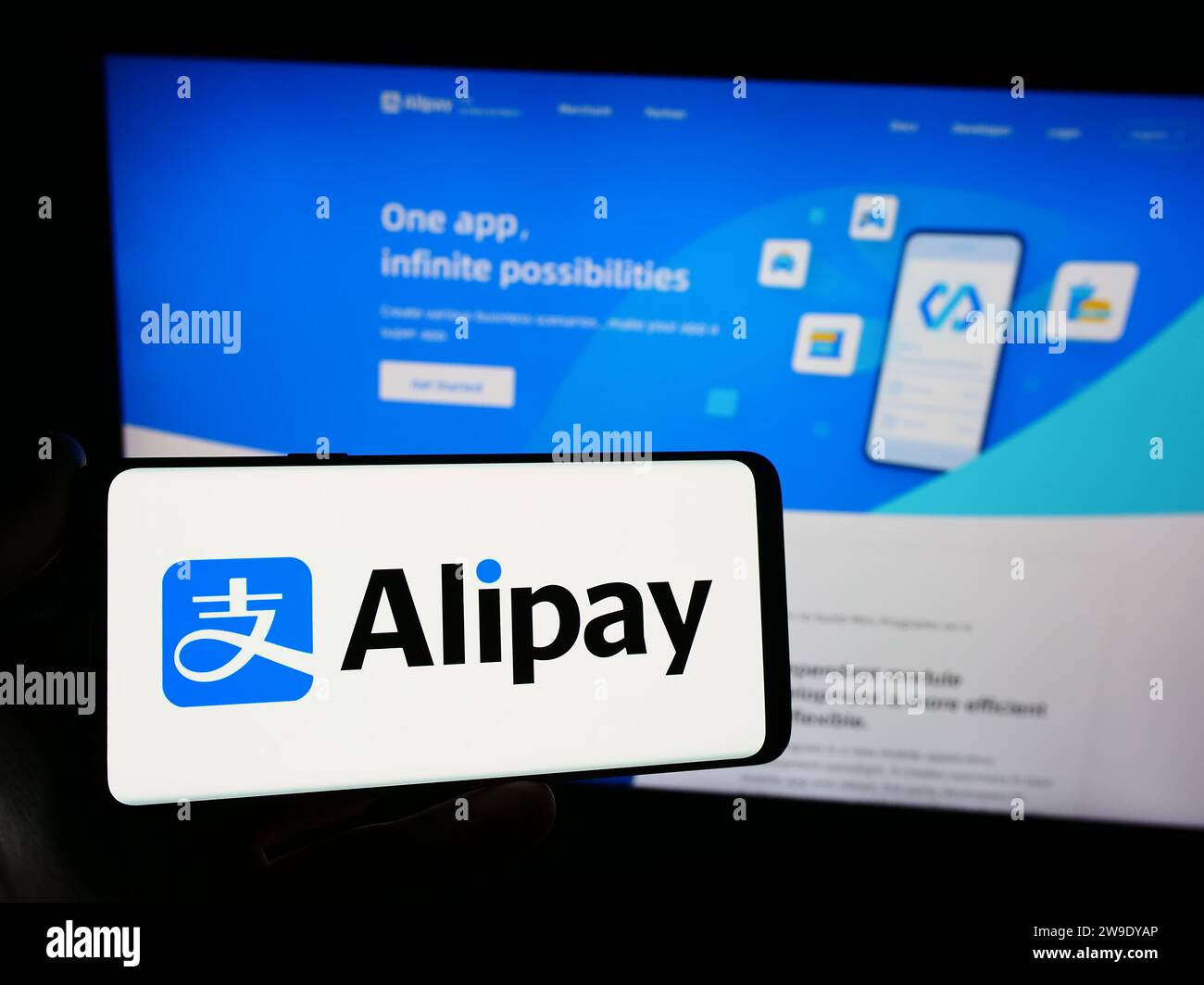 Personne détenant smartphone avec logo de la société chinoise de plate-forme de paiement Alipay en face du site Web. Concentrez-vous sur l'affichage du téléphone. Banque D'Images