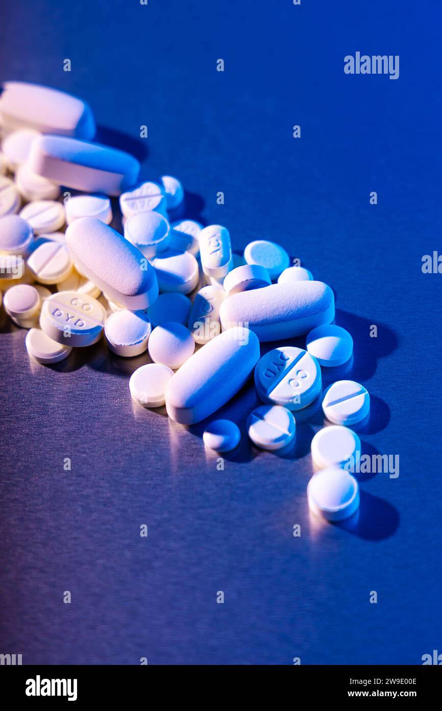 Pilules blanches et comprimés sur fond bleu Banque D'Images