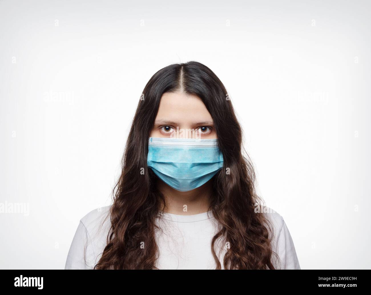 Une fille portant un masque médical protecteur sur fond blanc. La notion de maladies virales, épidémies et pandémies. Banque D'Images