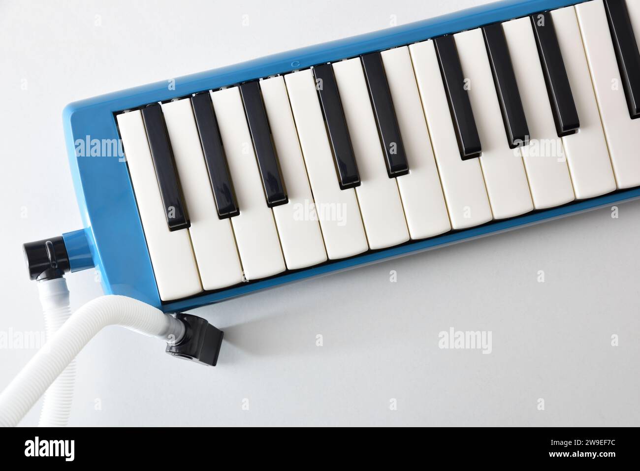 Détail de melodica bleu préparé à jouer sur la table avec tube de soufflage sur la table isolée blanche. Vue de dessus. Banque D'Images