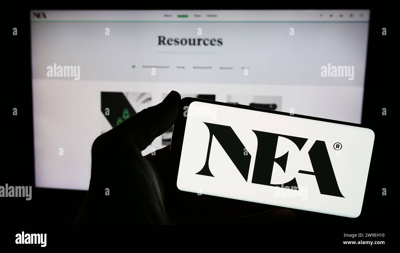 Personne détenant un téléphone intelligent avec le logo de la société d'investissement New Enterprise Associates Inc. (NEA) devant le site Web. Concentrez-vous sur l'affichage du téléphone. Banque D'Images