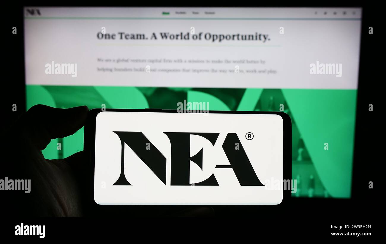 Personne détenant un téléphone cellulaire avec le logo de la société d'investissement New Enterprise Associates Inc. (NEA) devant la page Web. Concentrez-vous sur l'affichage du téléphone. Banque D'Images