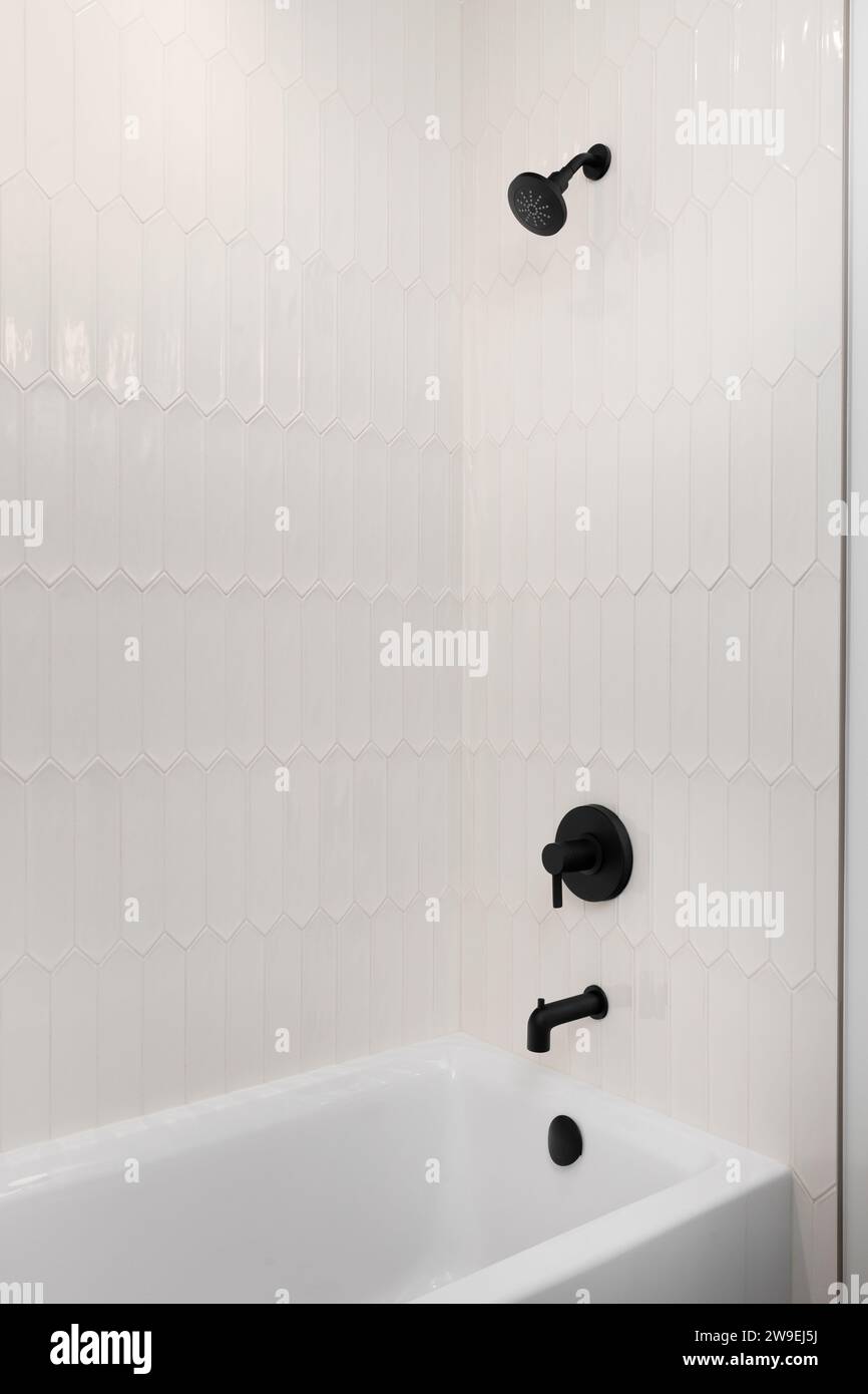 Une douche et une baignoire avec carreaux de piquet de couleur beige et robinet noir et pomme de douche. Banque D'Images