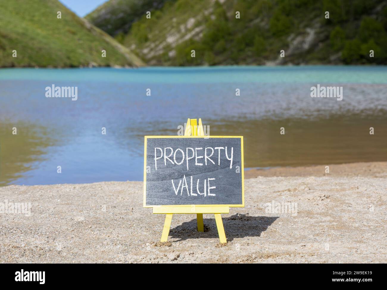 Symbole de valeur de propriété. Mots conceptuels valeur de la propriété sur beau tableau noir de craie. Beau fond de lac de montagne de plage de sable. Prope d'affaires Banque D'Images