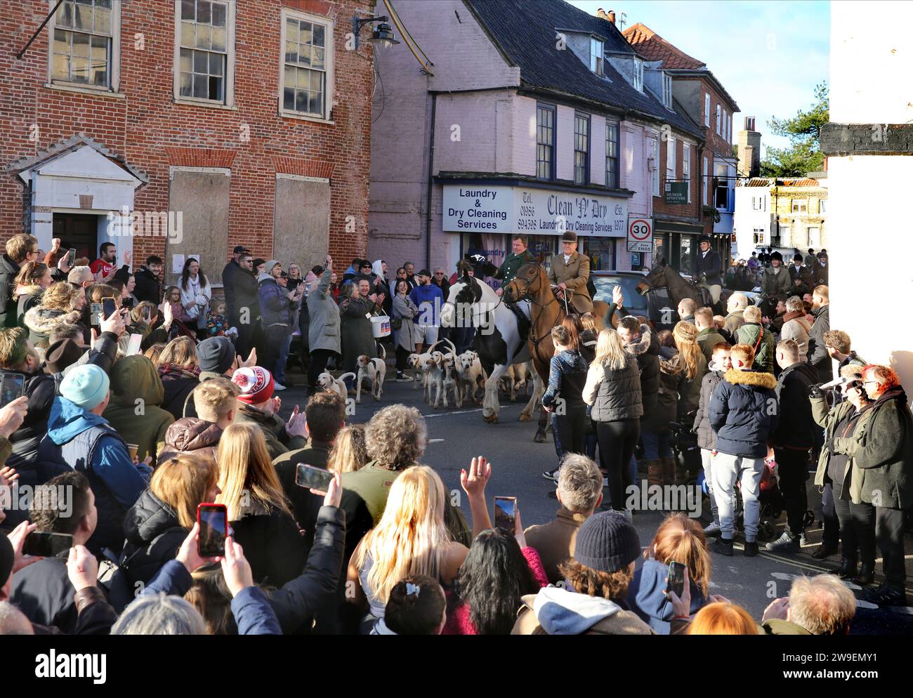 Bungay, Suffolk, Royaume-Uni. 26 décembre 2023. Cavaliers et chiens défilent dans les rues bordées de partisans de la chasse pendant le défilé de chasse du lendemain de Noël. Action contre la cruauté envers les animaux, une manifestation a eu lieu dans le centre-ville de Bungay alors que les Harriers de Waveney et Norfolk défilent dans les rues pour soutenir la campagne. Les manifestants ont déclaré que, bien qu'il s'agisse d'une interdiction de la chasse traditionnelle au renard, les animaux sont toujours tués pendant l'alternative de la chasse au sentier et ils appellent à une interdiction totale. (Image de crédit : © Martin Pope/SOPA Images via ZUMA Press Wire) USAGE ÉDITORIAL SEULEMENT! Pas pour Co Banque D'Images