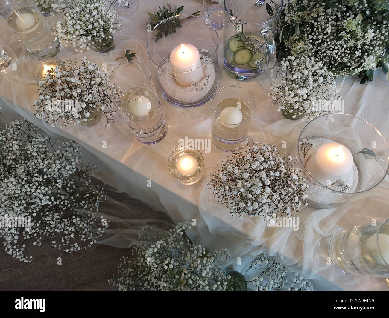 Une table élégamment décorée pour une occasion spéciale, avec des bougies allumées, des fleurs fraîches et d'autres éléments décoratifs Banque D'Images