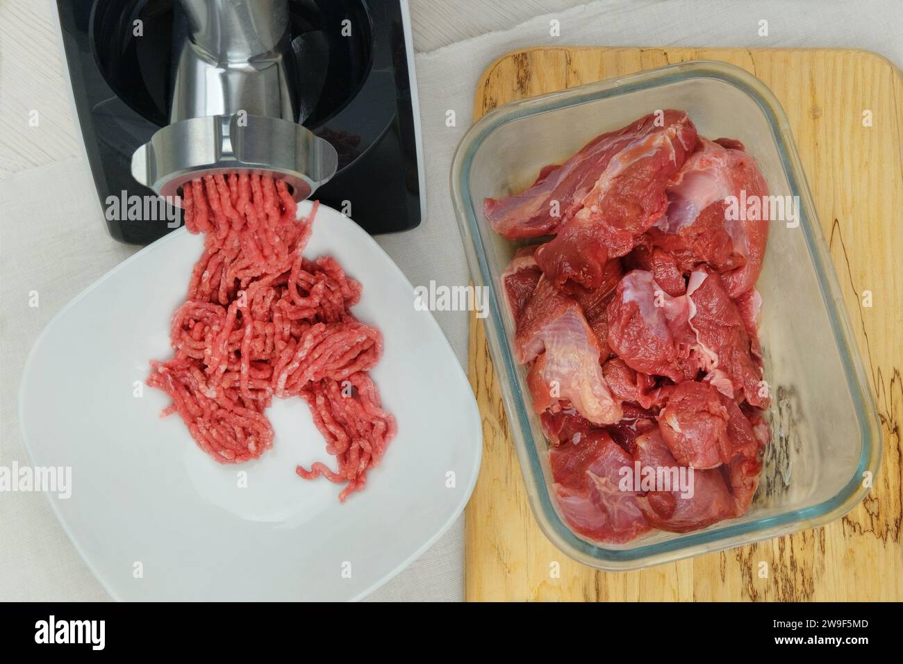 Hachez la viande dans un bol avec hachoir à viande électrique à l'intérieur de la cuisine. Le bœuf haché maison sort du hachoir à viande. Cuisiner à la maison. Banque D'Images