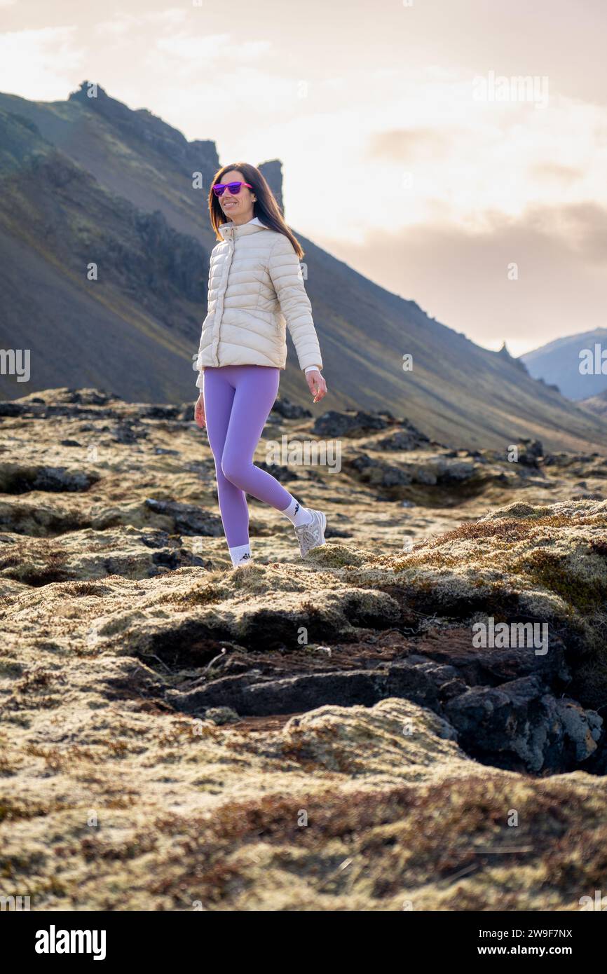 Femme avec des leggings violets marchant dans un champ de lave, Islande Banque D'Images