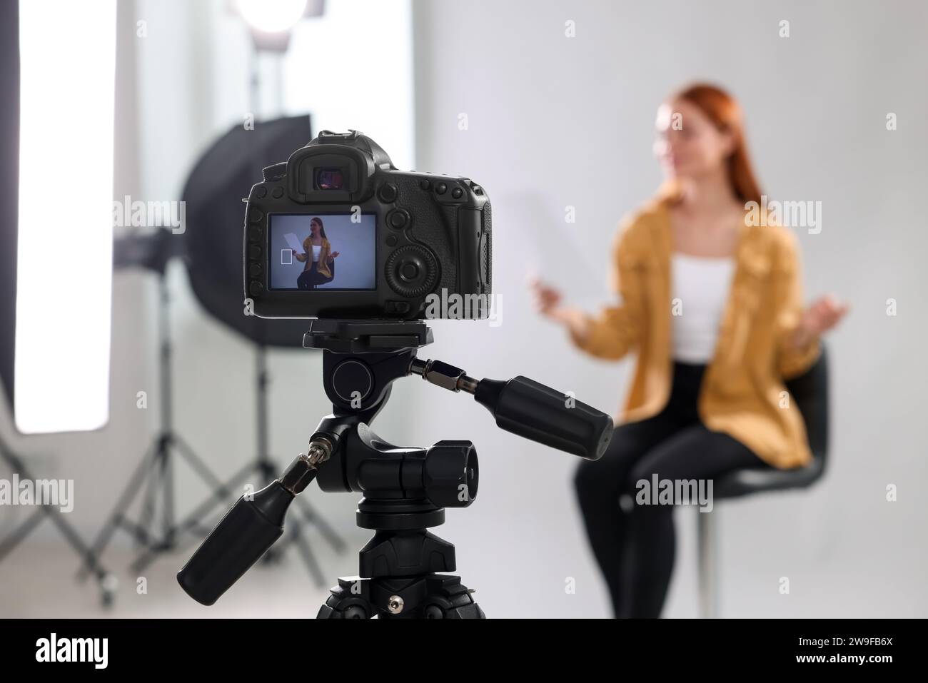 Appel de casting. Femme jouant devant la caméra sur fond gris clair au studio, mise au point sélective Banque D'Images