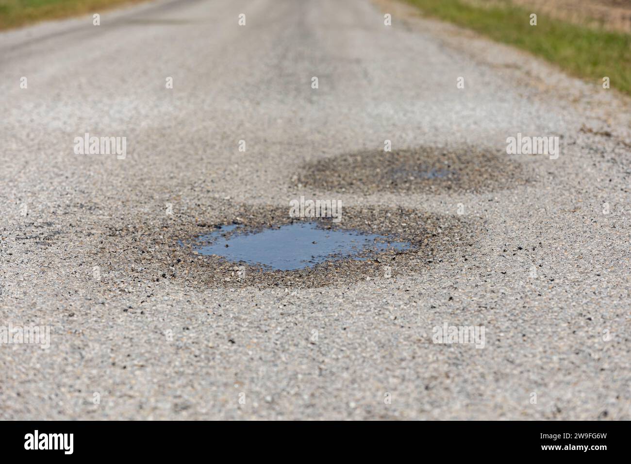 Gros plan de la cagoule, trou de chuckhole, sur la chaussée asphaltée. Concept de réparation, d'entretien et de dommages de rue. Banque D'Images