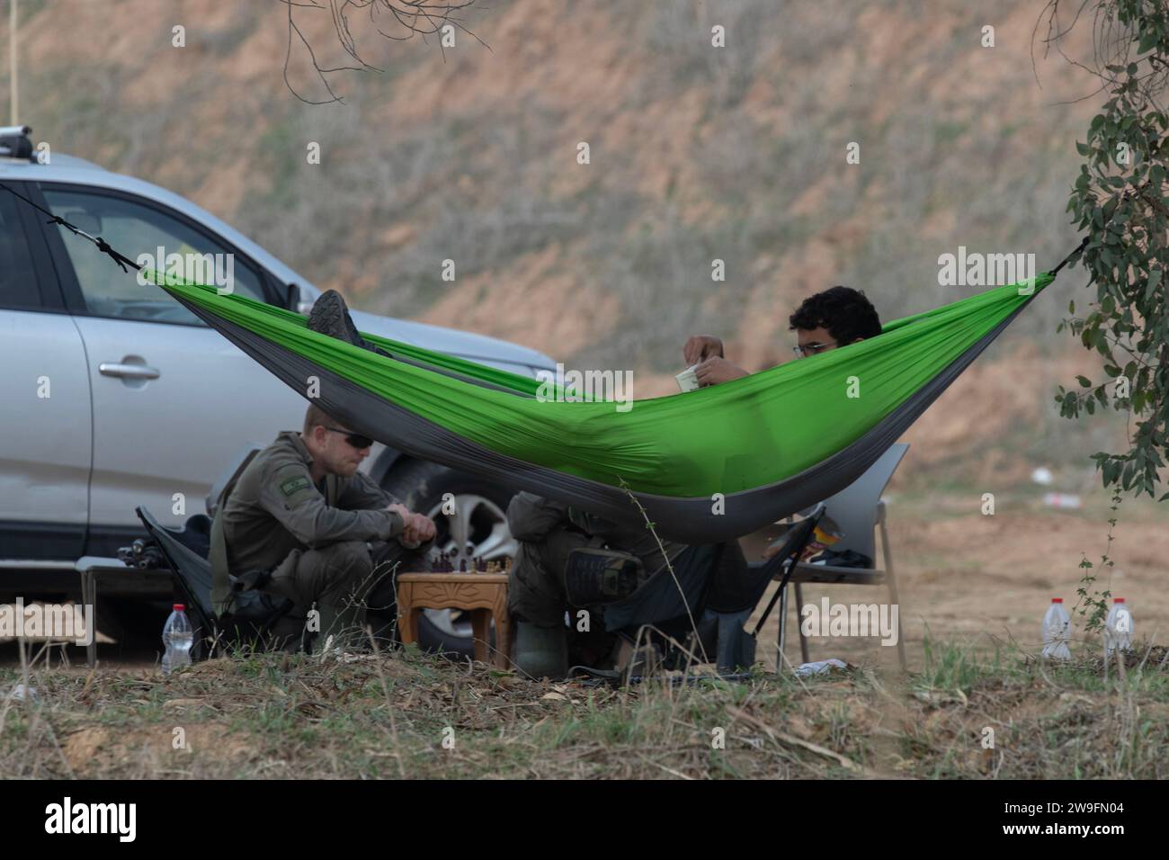 Sud Israël, Israël. 27 décembre 2023. Les soldats de l’infanterie israélienne se détendent sur une aire de rassemblement dans le sud d’Israël près de la frontière avec la bande de Gaza alors qu’ils passent le temps à jouer aux échecs et à lire dans un hamac le mercredi 27 décembre 2023. L’armée israélienne a déclaré qu’il faudra des mois de plus pour atteindre ses objectifs de détruire le Hamas et de s’assurer qu’il ne pourra plus jamais attaquer Israël comme il l’a fait le 7 octobre 2023. Photo de Jim Hollander/UPI crédit : UPI/Alamy Live News Banque D'Images