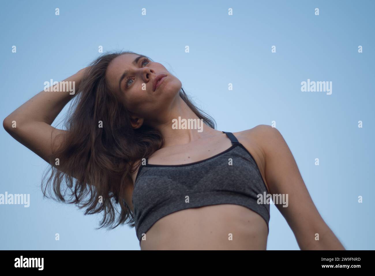 Une jeune femme blanche qui s'étire dans un soutien-gorge de sport Banque D'Images