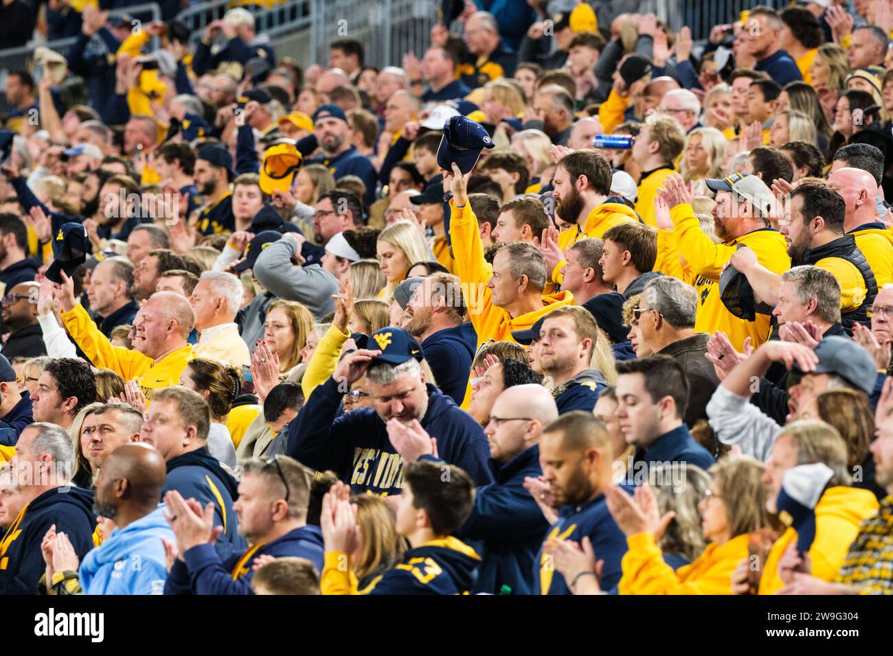 Charlotte, Caroline du Nord, États-Unis. 27 décembre 2023. Les fans de West Virginia Mountaineers lèvent leur chapeau après le chant de l'hymne national pour commencer le Dukes Mayo Bowl 2023 contre les North Carolina Tar Heels (crédit image : © Maxwell Vittorio/ZUMA Press Wire) À USAGE ÉDITORIAL SEULEMENT! Non destiné à UN USAGE commercial ! Banque D'Images