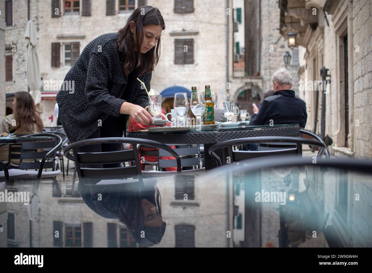 Kotor, Monténégro, 17 avril 2023 : serveuse défrichant une table dans un café en plein air placé sur la place de la ville Banque D'Images