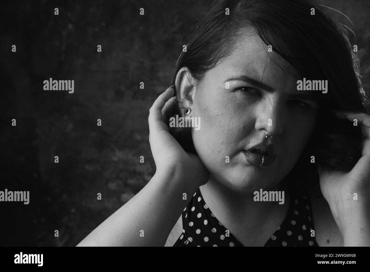 portrait noir et blanc de belle jeune femme de taille plus avec les cheveux courts posant avec ses mains sur sa tête, regardant la caméra, image avec copie spac Banque D'Images