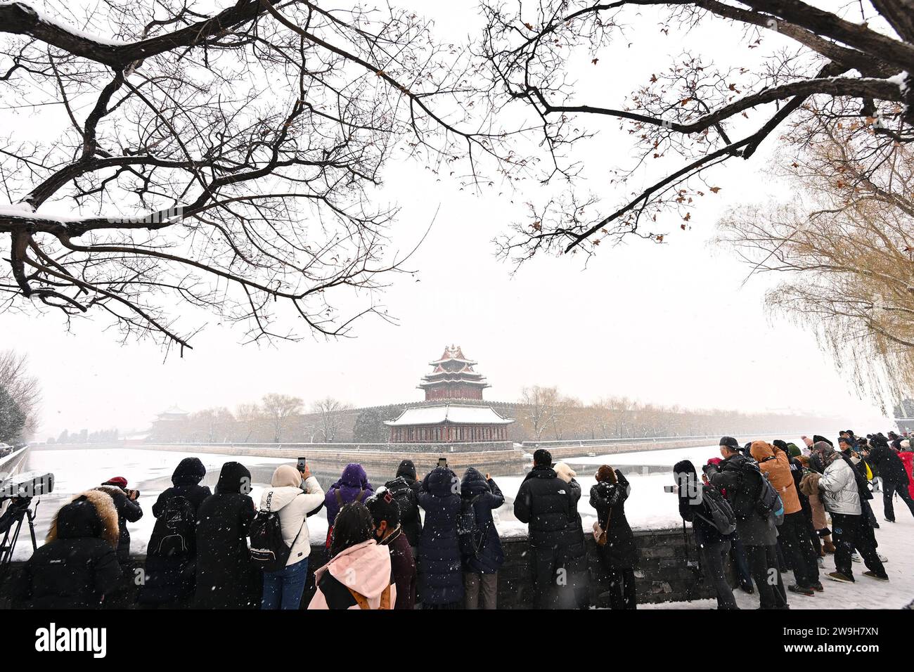 (231228) -- PÉKIN, 28 déc. 2023 (Xinhua) -- les visiteurs prennent des photos devant une tourelle du musée du palais dans les chutes de neige à Beijing, capitale de la Chine, le 13 décembre 2023. Créé sous la dynastie Yuan (1271-1368), l'axe central de Pékin, ou Zhongzhouxian, s'étend sur 7,8 kilomètres entre la porte de Yongding au sud de la ville et la Tour du tambour et du clocher au nord. La plupart des grands bâtiments de la vieille ville de Pékin se trouvent le long de cet axe. Portes, palais, temples, places et jardins de la vieille ville sont tous reliés à l'axe. Comme ils ont été témoins des activités folkloriques le long de la ligne f Banque D'Images