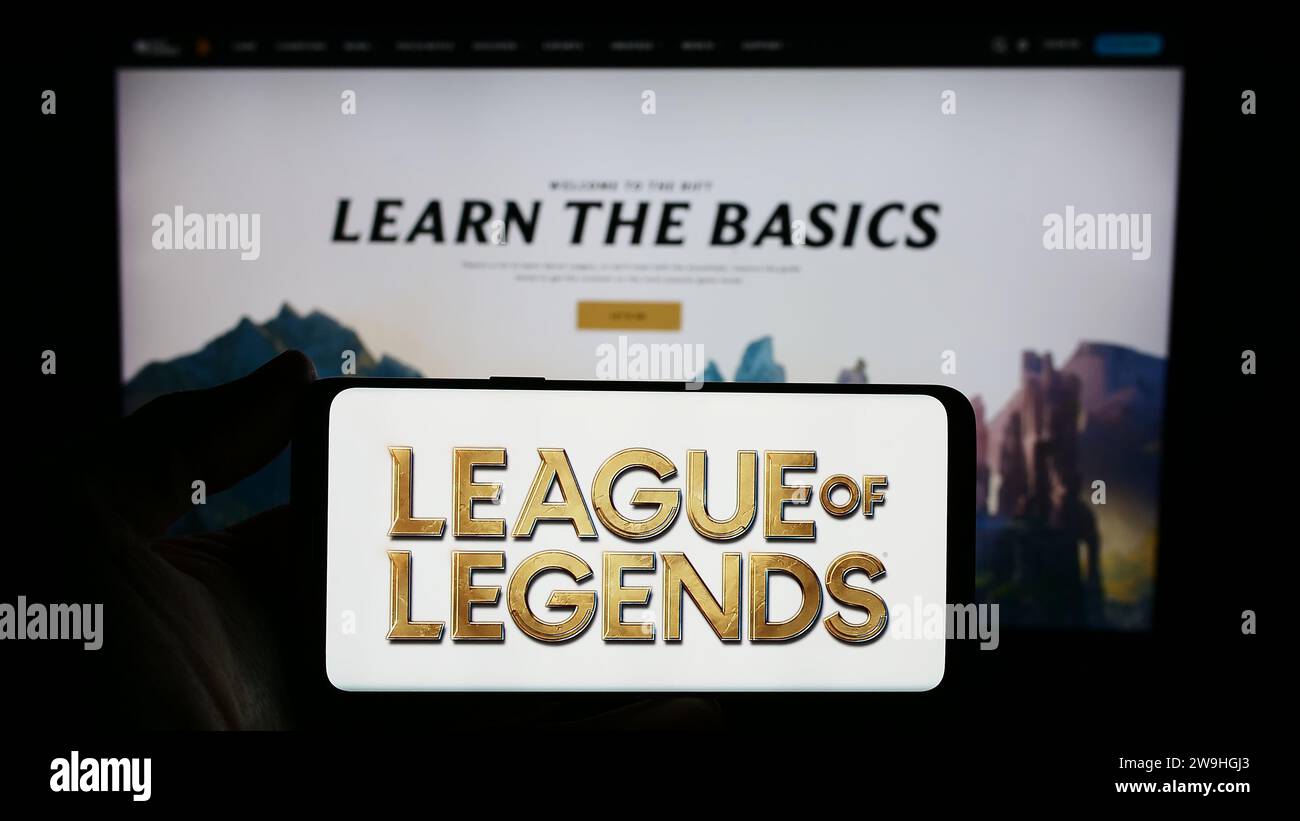 Personne tenant le smartphone avec le logo du jeu vidéo multijoueur en ligne League of Legends (LOL) en face du site Web. Concentrez-vous sur l'affichage du téléphone. Banque D'Images