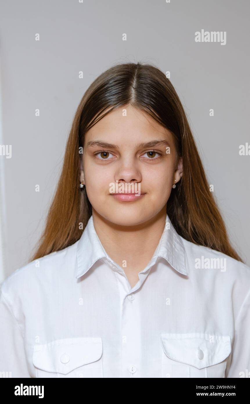 Portrait d'une fille de quatorze ans dans une chemise blanche sur fond gris Banque D'Images