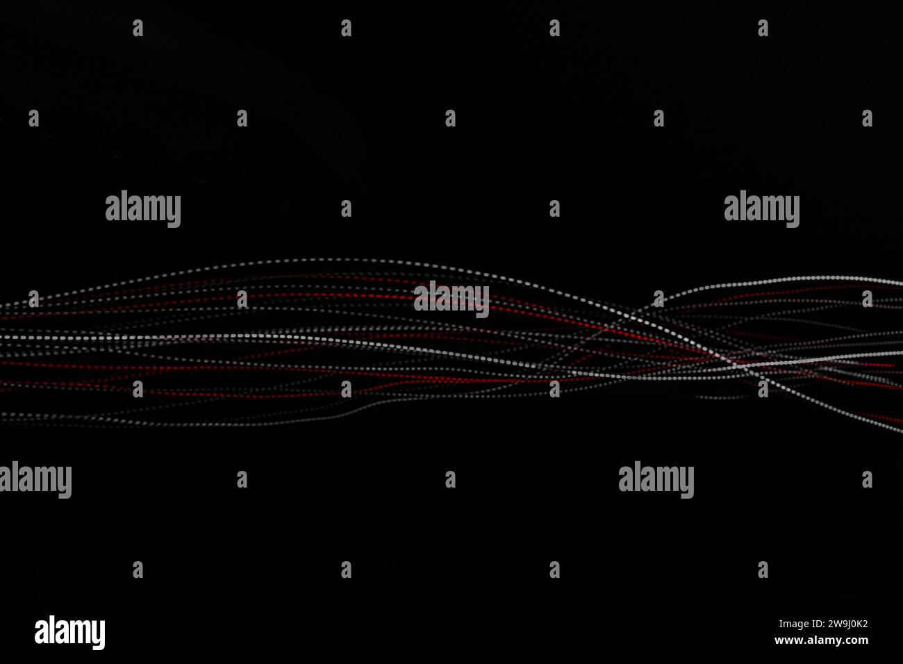Une photographie de lumières rouges et blanches éclatantes dans une photo à exposition longue. Motif de lignes pointillées, vagues de couleur. Photographie de peinture légère Banque D'Images