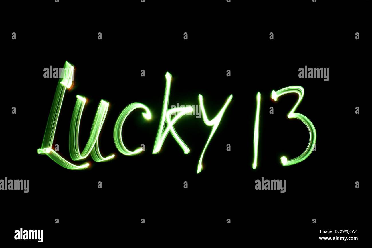 Photographie des mots « Lucky 13 » écrits en lumière verte éclatante sur une photo à exposition longue sur fond noir. Photographie de peinture légère Banque D'Images